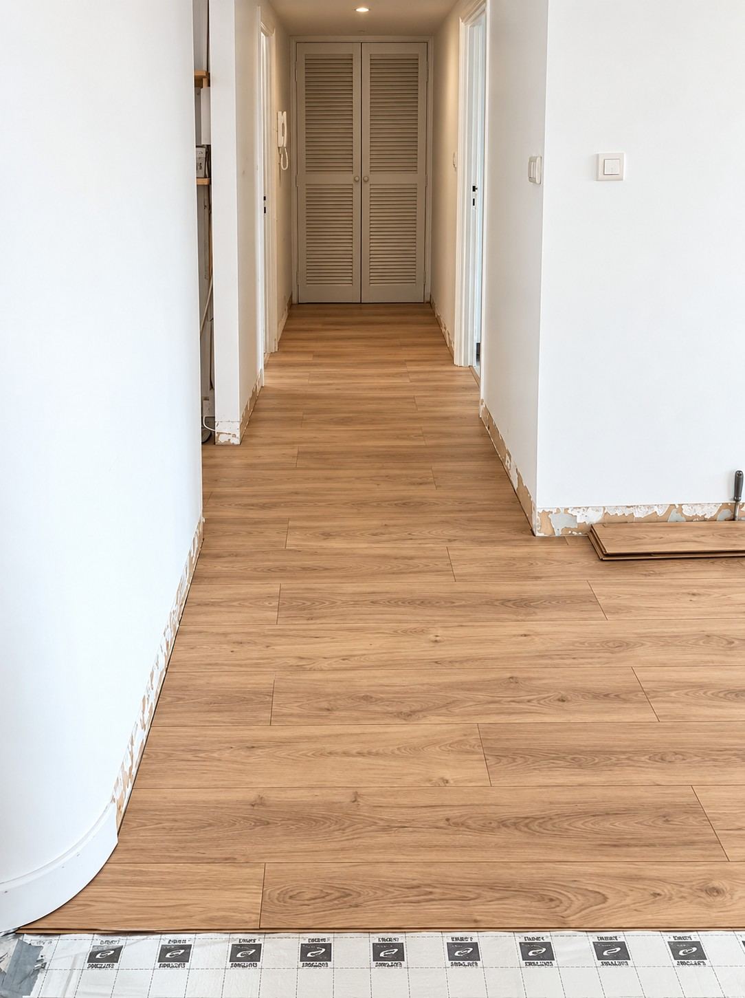 Les anciennes plinthes ont été déposées : le parquet file jusque sous la plinthe neuve, qui couvrira le jeu de dilatation contre le mur.