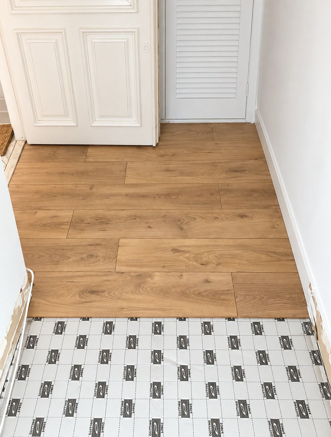 À l'entrée, les lames viennent au ras des huisseries ; le raccord avec le carrelage du palier se fera par une barre de seuil.